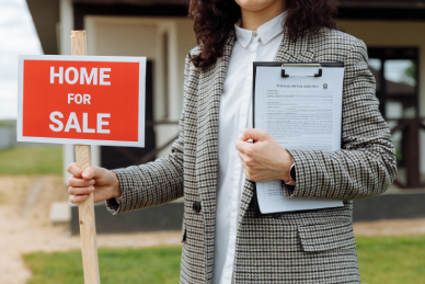  Woman holding a home for sale sign